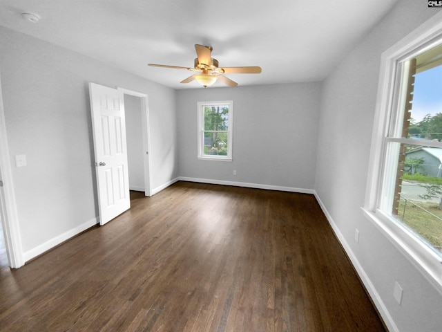 empty room featuring ceiling fan, dark wood finished floors, and baseboards