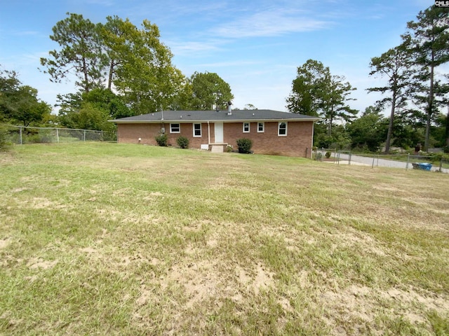 back of house with a fenced backyard, a yard, and brick siding