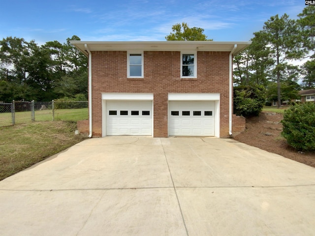 garage featuring fence and concrete driveway