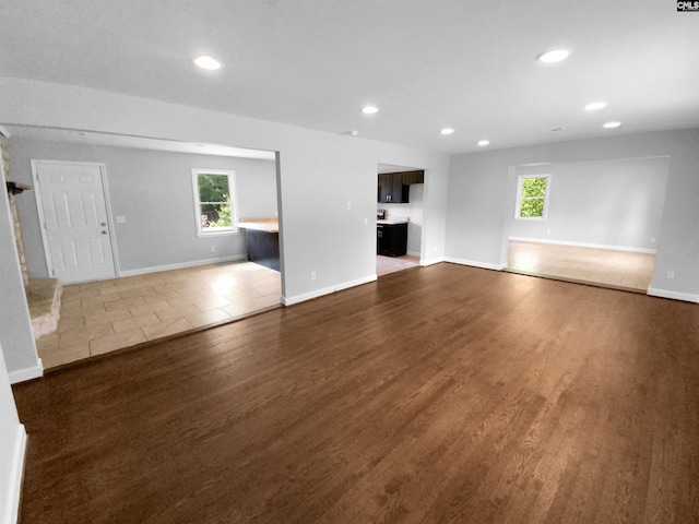 unfurnished living room with dark wood-style floors, a wealth of natural light, and recessed lighting