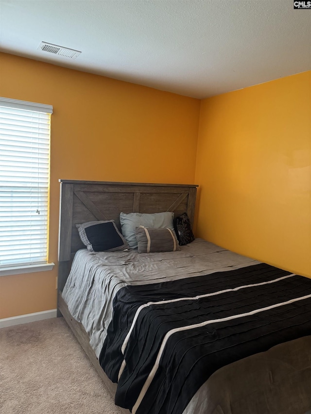 bedroom with baseboards, visible vents, and light colored carpet