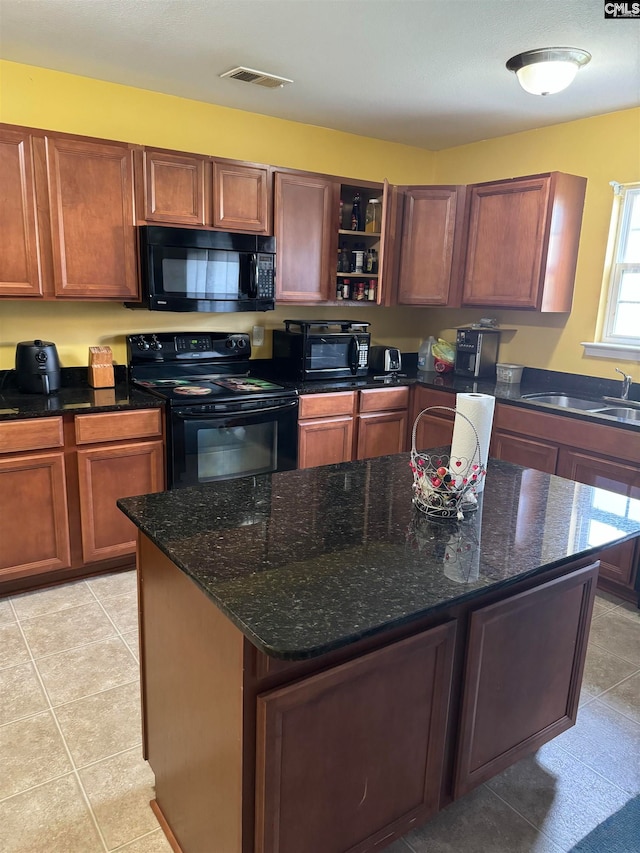 kitchen with sink, a center island, light tile patterned floors, and black appliances