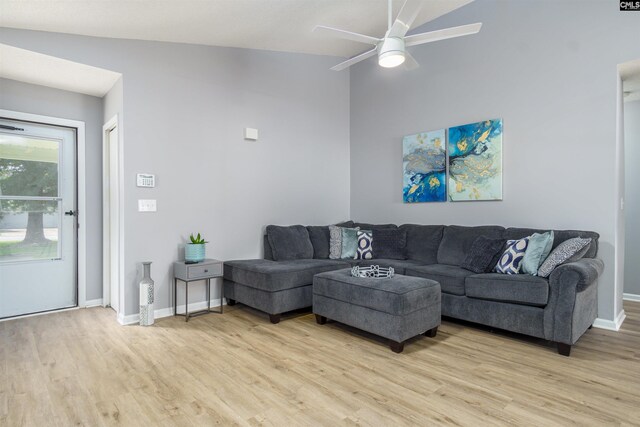 living room with ceiling fan, light wood-type flooring, a textured ceiling, and high vaulted ceiling