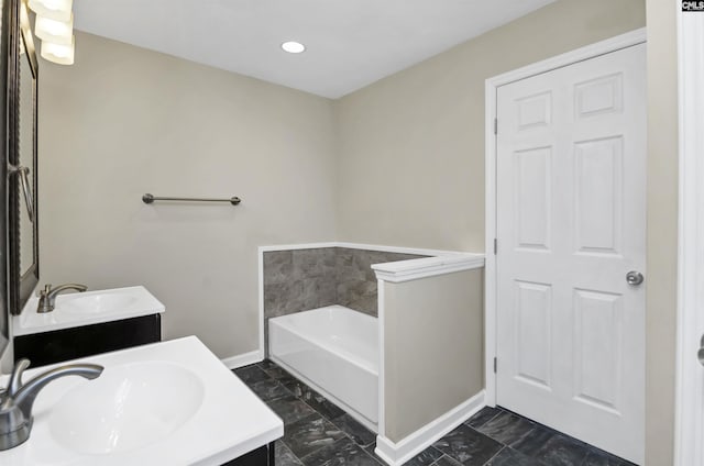 bathroom with vanity, a garden tub, baseboards, and marble finish floor