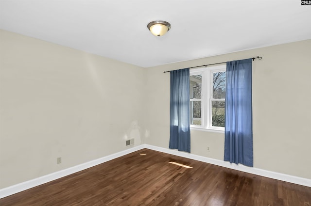 unfurnished room with visible vents, baseboards, and dark wood finished floors