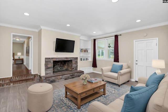 living room featuring crown molding, baseboards, a stone fireplace, recessed lighting, and wood finished floors