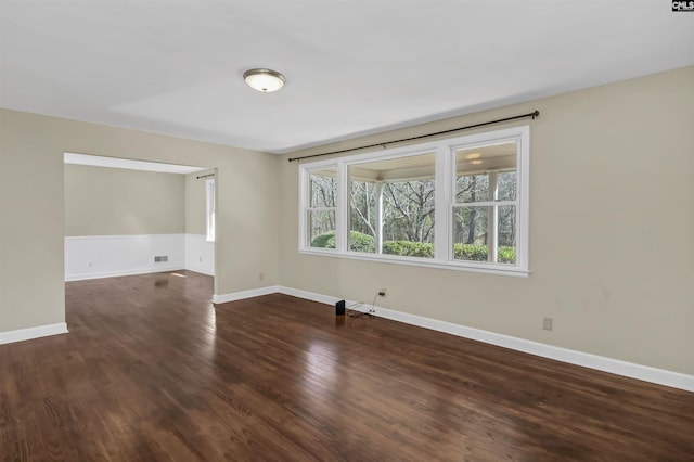 spare room with wood finished floors, visible vents, and baseboards