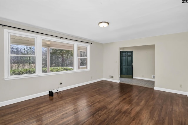 empty room featuring visible vents, baseboards, and wood finished floors