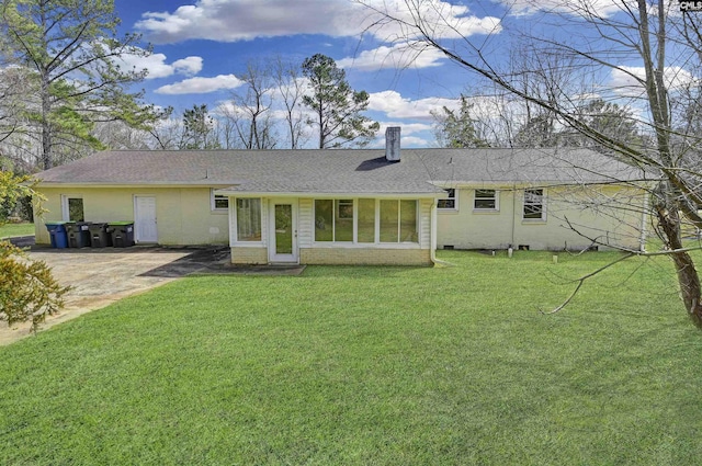 back of property featuring brick siding, a chimney, a lawn, and a shingled roof