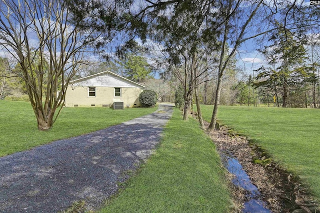 view of yard featuring aphalt driveway and central AC