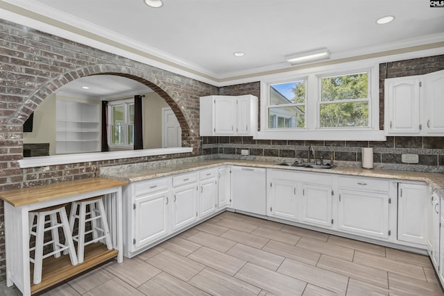 kitchen featuring a sink, backsplash, white cabinetry, and white dishwasher