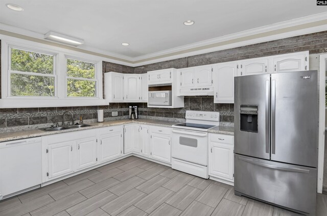 kitchen featuring white appliances, a sink, decorative backsplash, white cabinets, and under cabinet range hood