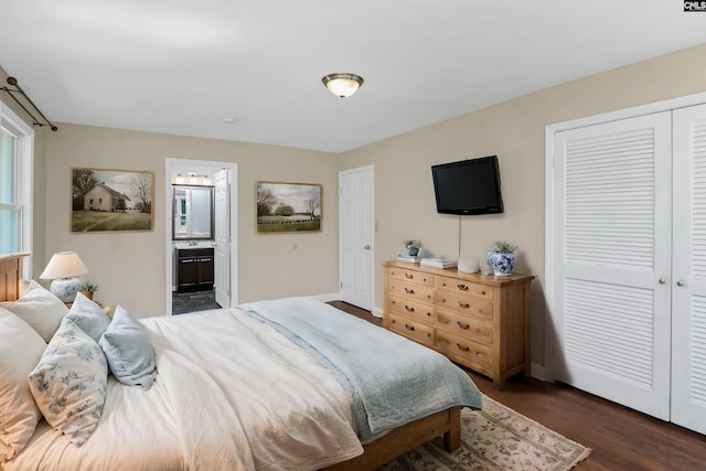 bedroom with a closet, dark wood-type flooring, and ensuite bath