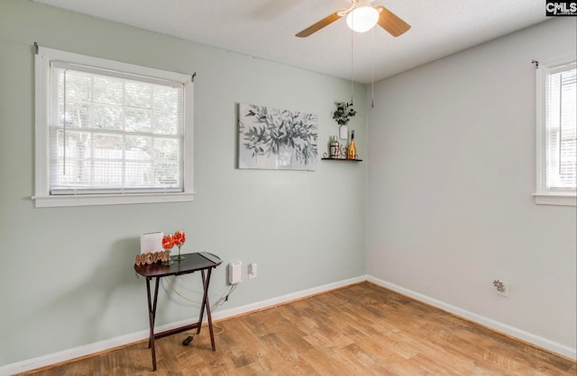 empty room featuring a wealth of natural light, hardwood / wood-style flooring, and ceiling fan