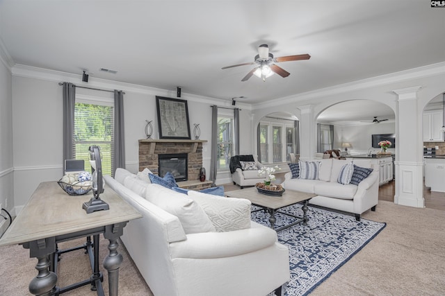 carpeted living room with arched walkways, a healthy amount of sunlight, a fireplace, and ceiling fan