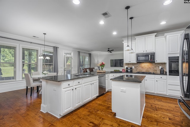 kitchen with a kitchen island, appliances with stainless steel finishes, decorative light fixtures, a peninsula, and white cabinetry