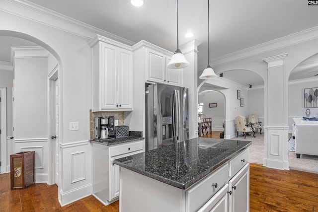 kitchen with hanging light fixtures, open floor plan, white cabinets, a kitchen island, and stainless steel fridge