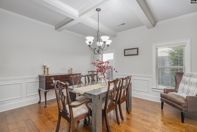 dining space featuring visible vents, ornamental molding, hardwood / wood-style floors, a chandelier, and beam ceiling