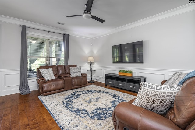 living area with dark wood-style flooring, visible vents, a ceiling fan, ornamental molding, and wainscoting