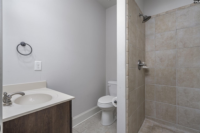 bathroom with toilet, vanity, baseboards, a tile shower, and tile patterned floors