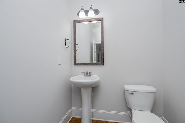 half bathroom featuring baseboards and toilet