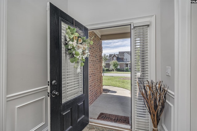 entrance foyer with brick wall, wainscoting, and a decorative wall