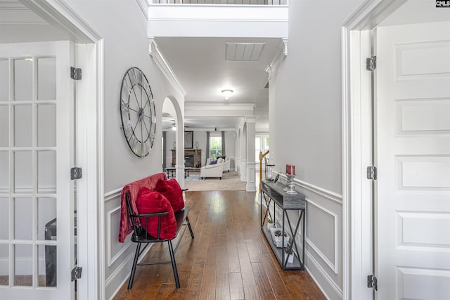 entryway featuring visible vents, a decorative wall, ornamental molding, dark wood-type flooring, and wainscoting