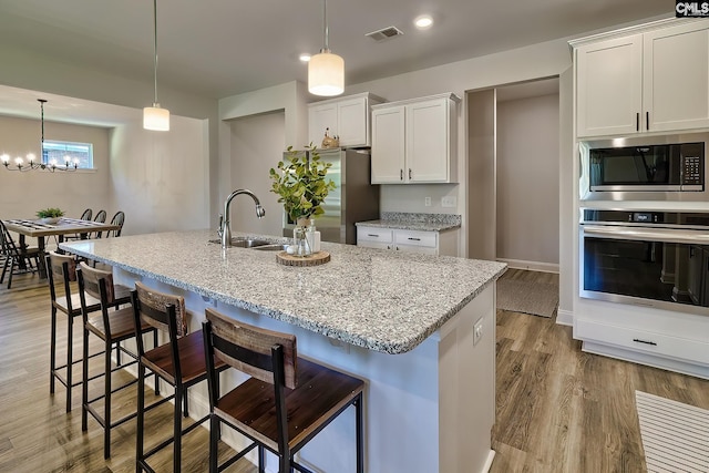 kitchen featuring sink, an inviting chandelier, light hardwood / wood-style flooring, stainless steel appliances, and pendant lighting