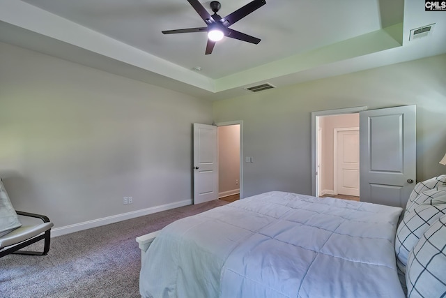 carpeted bedroom with a tray ceiling and ceiling fan