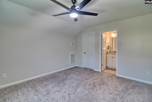 unfurnished bedroom with ceiling fan, vaulted ceiling, ensuite bath, and light carpet