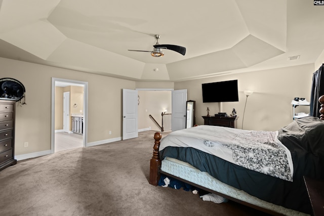 bedroom featuring a tray ceiling, ceiling fan, and ensuite bathroom