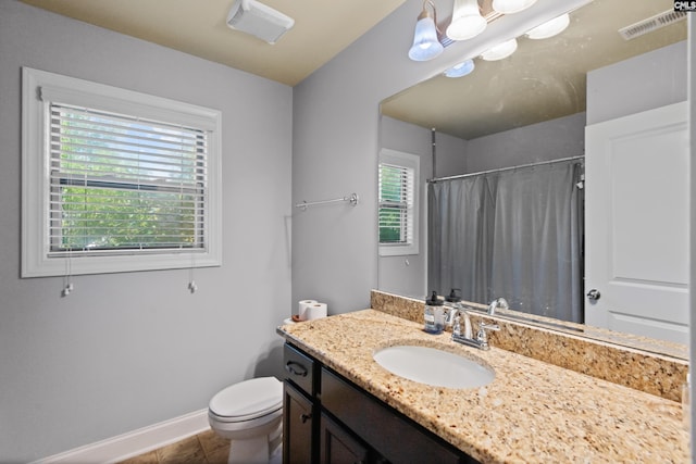 bathroom featuring tile patterned flooring, toilet, vanity, and a healthy amount of sunlight