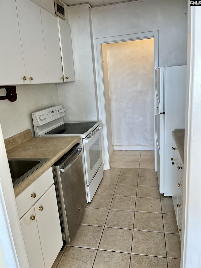 kitchen featuring white appliances, sink, light tile patterned floors, and white cabinets