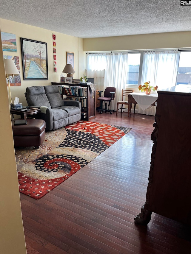 living room featuring a wealth of natural light, a textured ceiling, and dark hardwood / wood-style flooring