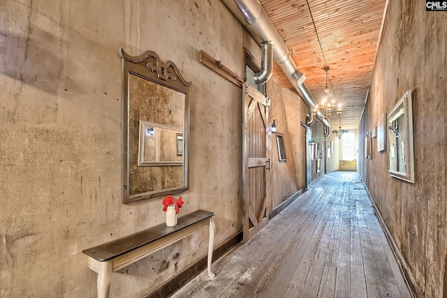 corridor with wooden ceiling, hardwood / wood-style flooring, a towering ceiling, and an inviting chandelier