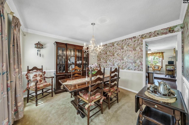 carpeted dining space with crown molding, wainscoting, a chandelier, baseboards, and wallpapered walls