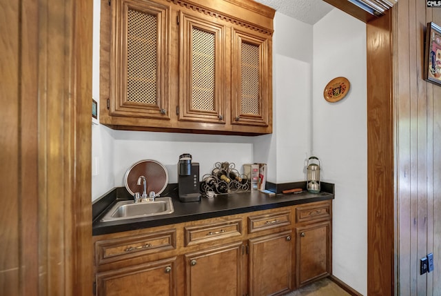 bar featuring a textured ceiling and a sink