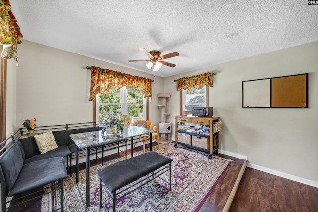 dining room with ceiling fan, a textured ceiling, baseboards, and wood finished floors