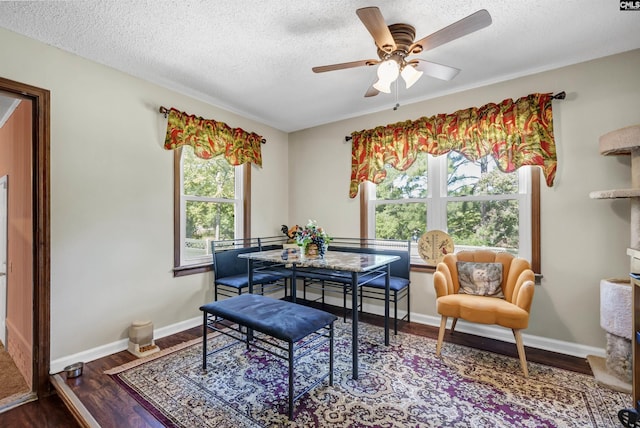 dining area featuring a textured ceiling, baseboards, and wood finished floors