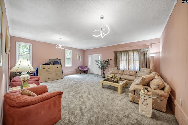 living room with an inviting chandelier, a textured ceiling, and carpet flooring