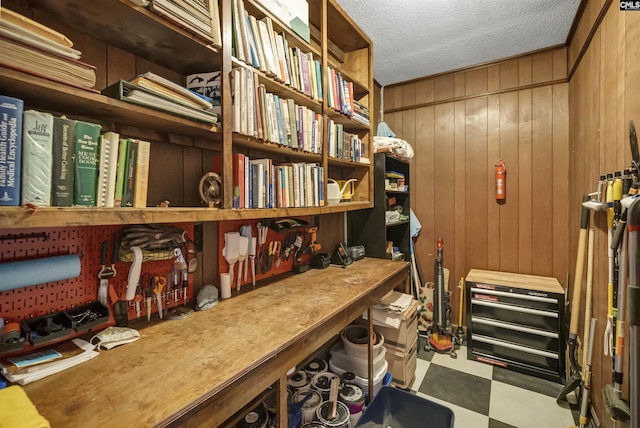 office featuring a textured ceiling, wood walls, a workshop area, and tile patterned floors