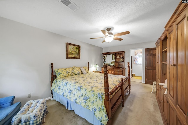 bedroom featuring a ceiling fan, light colored carpet, visible vents, and a textured ceiling