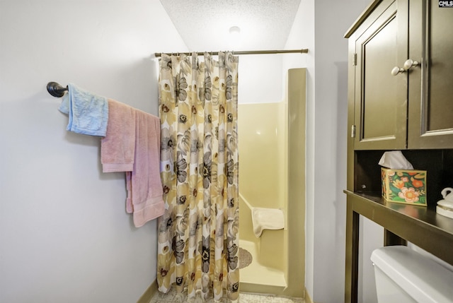 full bath with toilet, a stall shower, and a textured ceiling