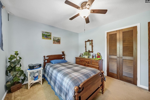 bedroom with a ceiling fan, a closet, light carpet, and baseboards