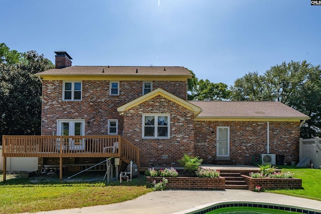 back of property featuring a deck, a patio, brick siding, a yard, and a chimney