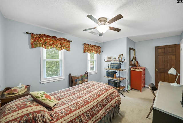 bedroom featuring a textured ceiling, a ceiling fan, visible vents, and light colored carpet