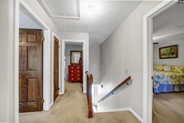 corridor with attic access, light colored carpet, and an upstairs landing