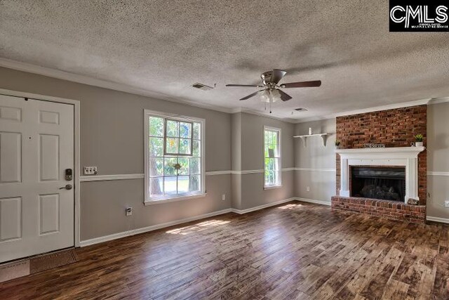 unfurnished living room featuring wood-type flooring, brick wall, a textured ceiling, and a brick fireplace