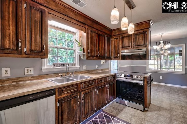 kitchen featuring a wealth of natural light, sink, stainless steel appliances, and decorative light fixtures