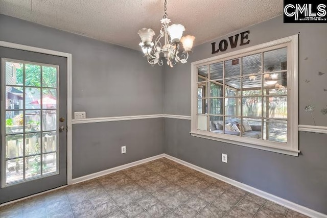 unfurnished dining area with a textured ceiling, an inviting chandelier, and tile patterned floors